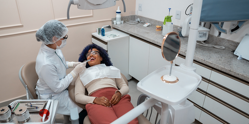 Dentist examining a reclining patient in a modern treatment room.
