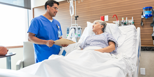 Emergency physician monitoring critical patient data on bedside screens.