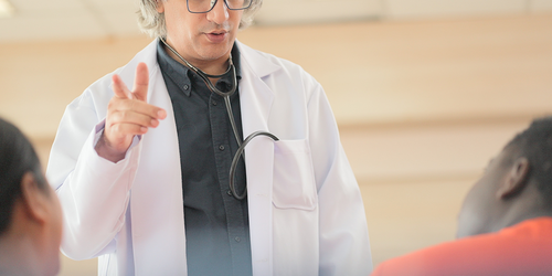 Internist checking a patient’s blood pressure in an exam room.