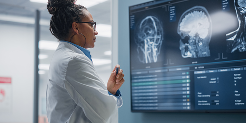 MRI technologist studying detailed brain scans on a large display.