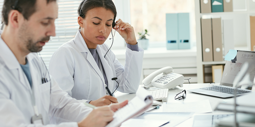 Healthcare workers transcribing medical information at office desks.