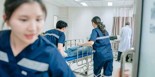 Medical staff pushing a hospital bed into an emergency room.