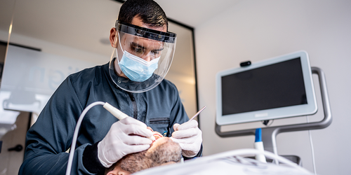 Orthodontist adjusting a patient’s teeth with dental instruments.
