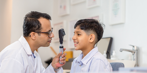 Eye specialist examining a child’s vision with a handheld device.