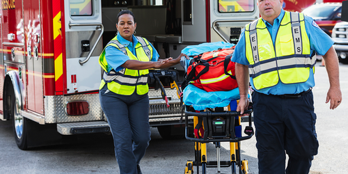 Paramedics moving a patient on a stretcher from an ambulance.