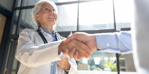 Healthcare professional shaking hands with a colleague in a hospital.