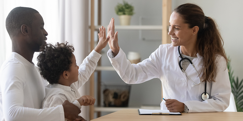 Pediatrician greeting a young child and parent in the office.