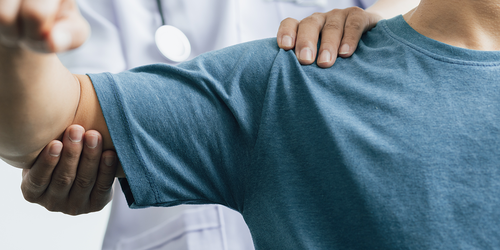 Rehab physician assessing a patient’s shoulder movement and range of motion.