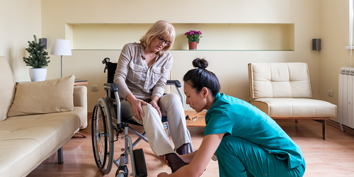 Physical therapist aide assisting a wheelchair user with footwear.