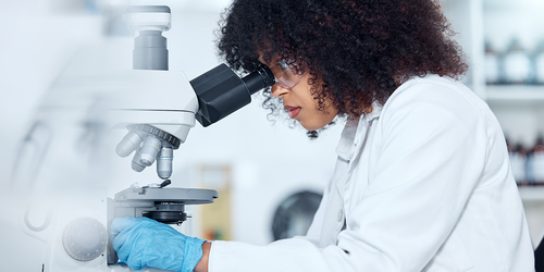 Pathologist examining samples with a microscope in a lab.
