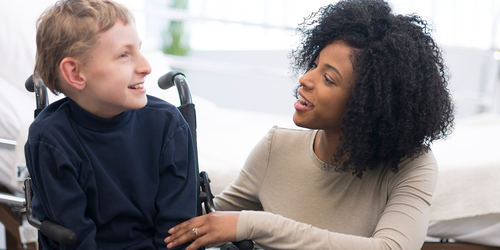 Psychiatric technician supporting a child in a wheelchair.