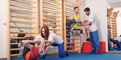 Recreational therapist guiding patients through therapeutic exercises on gym wall bars in a rehab center.