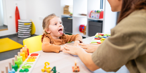Speech‑language pathology assistant with child using colorful learning toys.