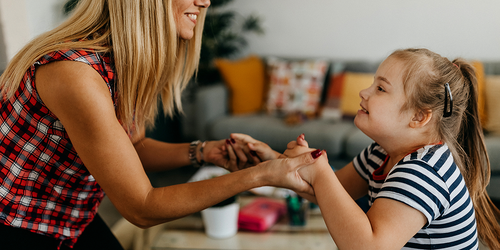 Therapist joyfully holding hands with a child during a session.