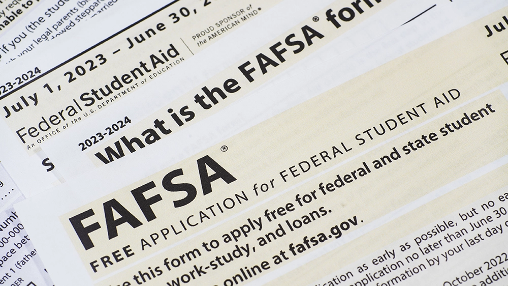 Close-up view of a financial aid application form with pen and glasses on a desk, representing college funding and student support resources